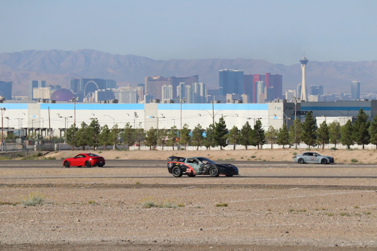 Black #22 C6 Corvette Z06 on track with the Las Vegas skyline behind