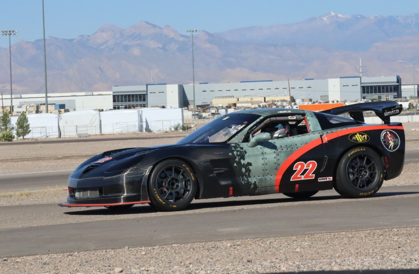 Black #22 C6 Corvette Z06 on track with mountains behind