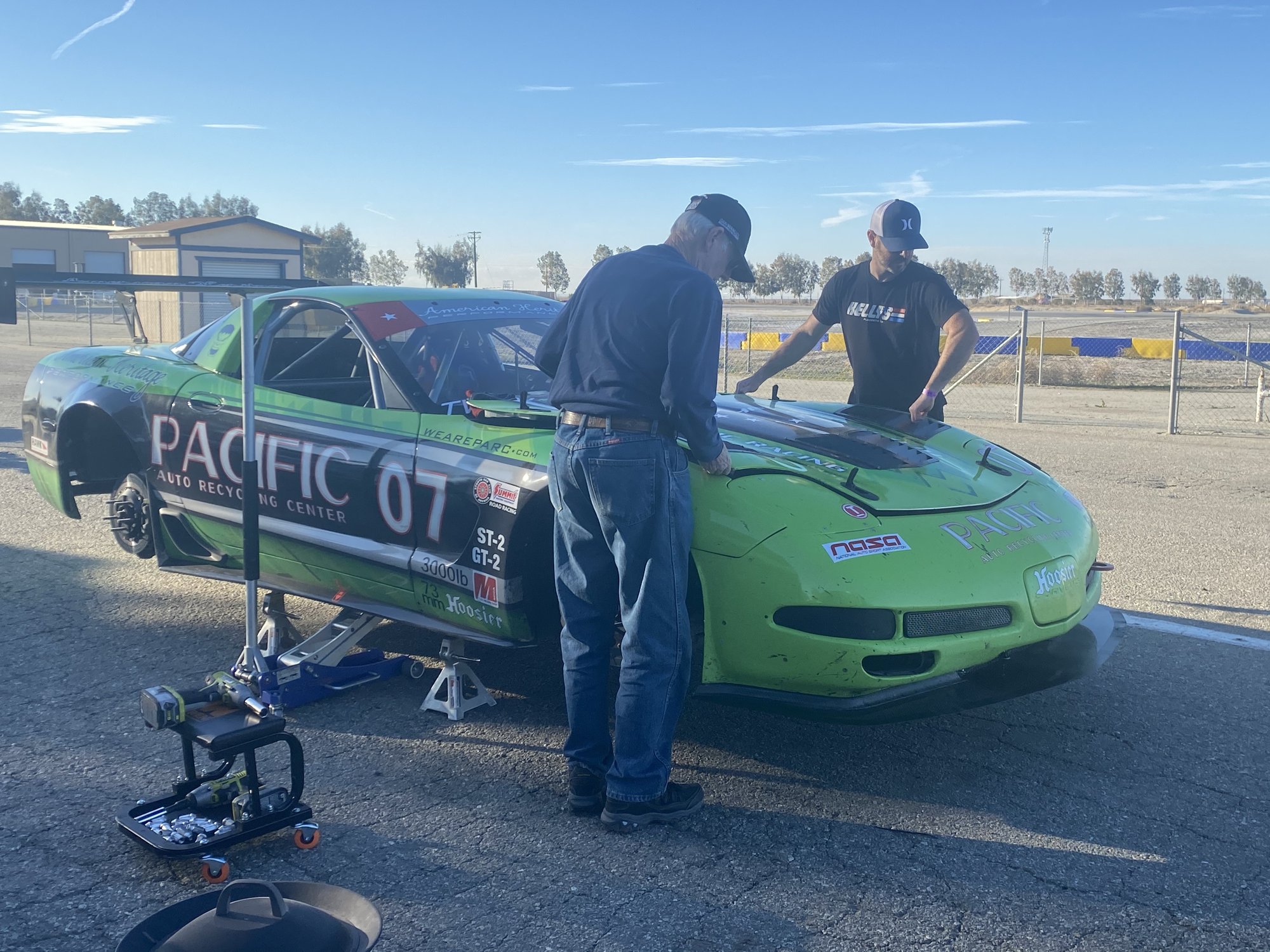 Crew working on the #07 C5 Corvette on jack stands at the track