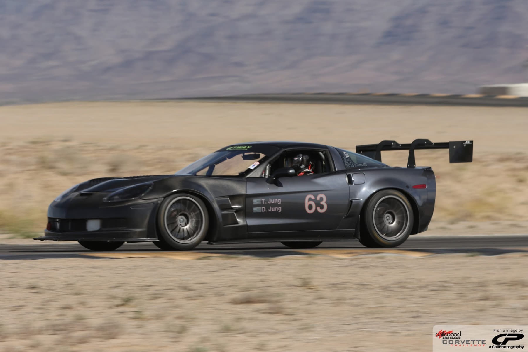 Gunmetal #63 C6 Corvette Z06 at speed on a desert circuit
