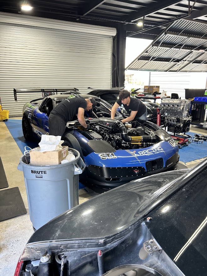 Mechanics working on a blue Corvette engine bay