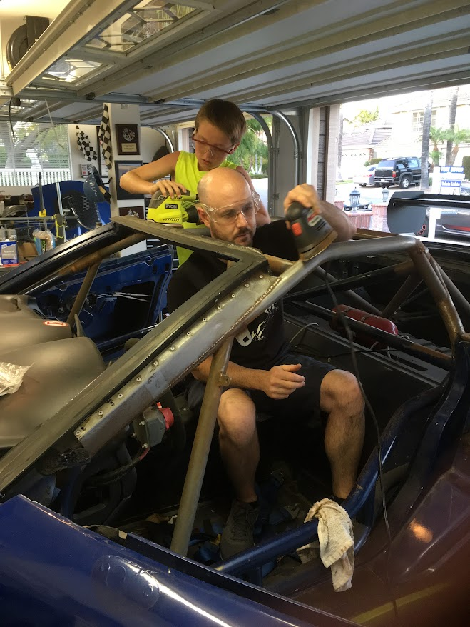 Fabrication work happening inside a blue race car cockpit
